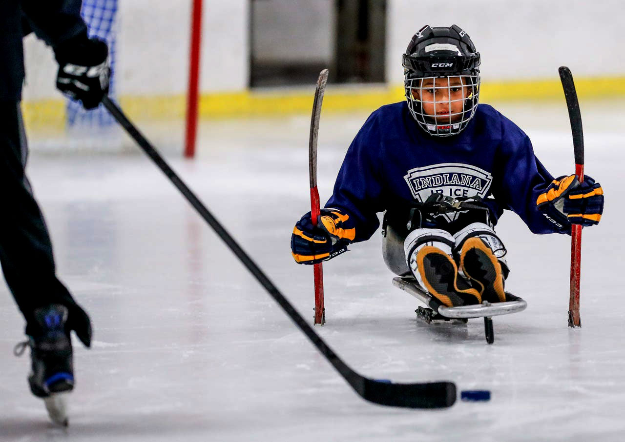 Young disabled child in hockey gear playing sled hockey